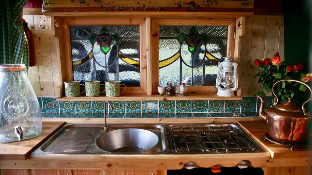 The kitchen of a citroen Relay conversion with stained glass and beautiful tiles and tea pot