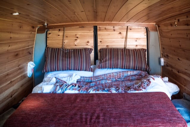 The bed inside of a Mercedes campervan converted into a quirky camper