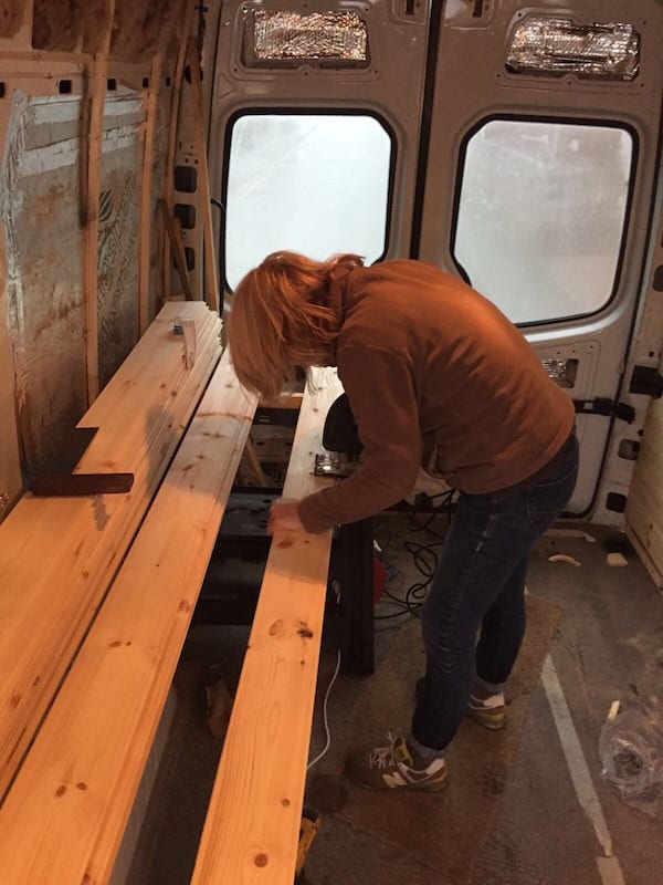 a man working on cutting wood inside a van