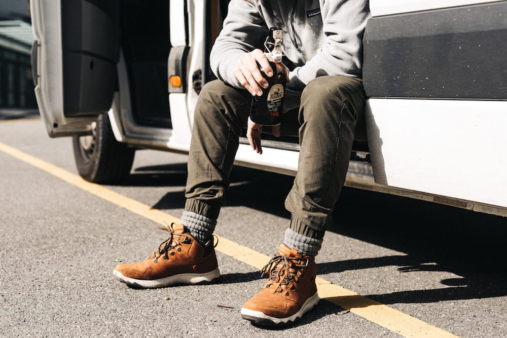 a man with a bottle in his hand sat on the steps of a campervan