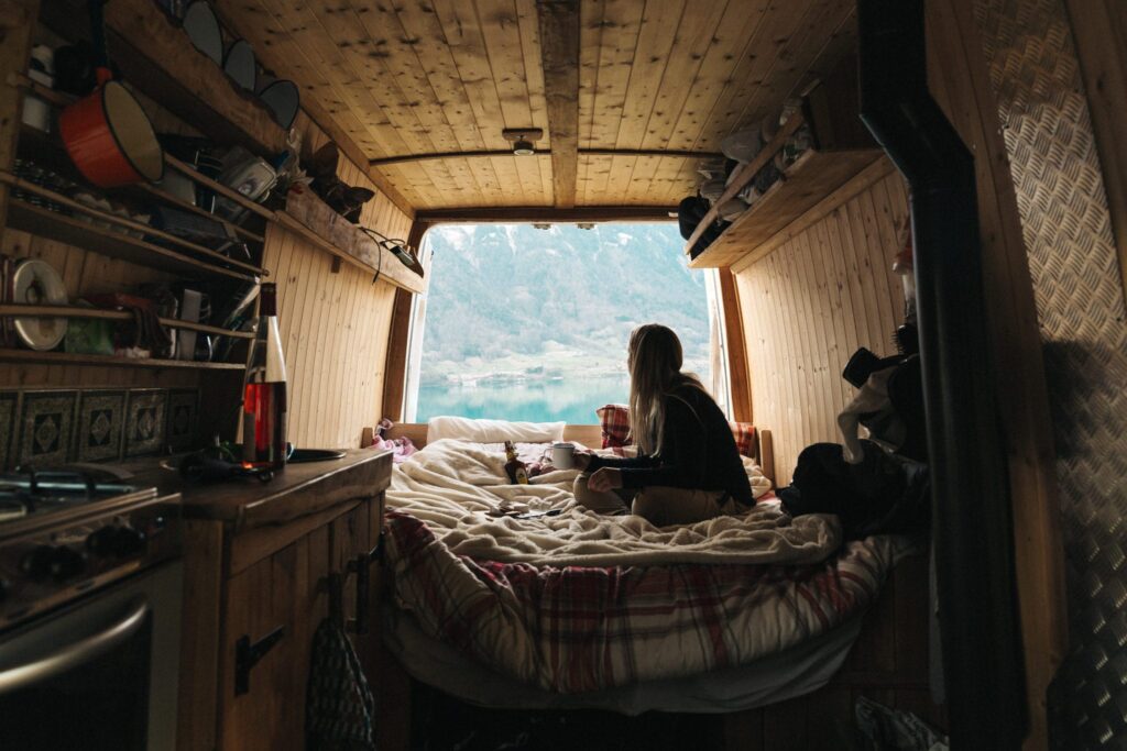 a woman sat on a bed in the back of a self built campervan