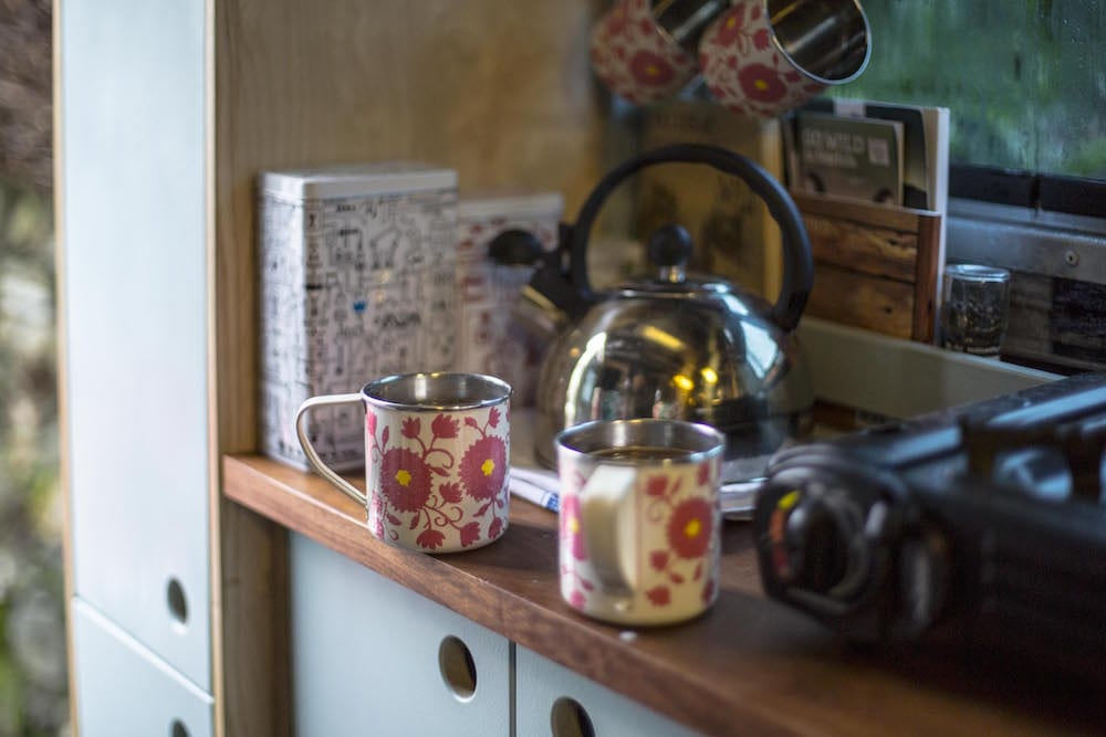 two mugs of coffee and a kettle in a campervan