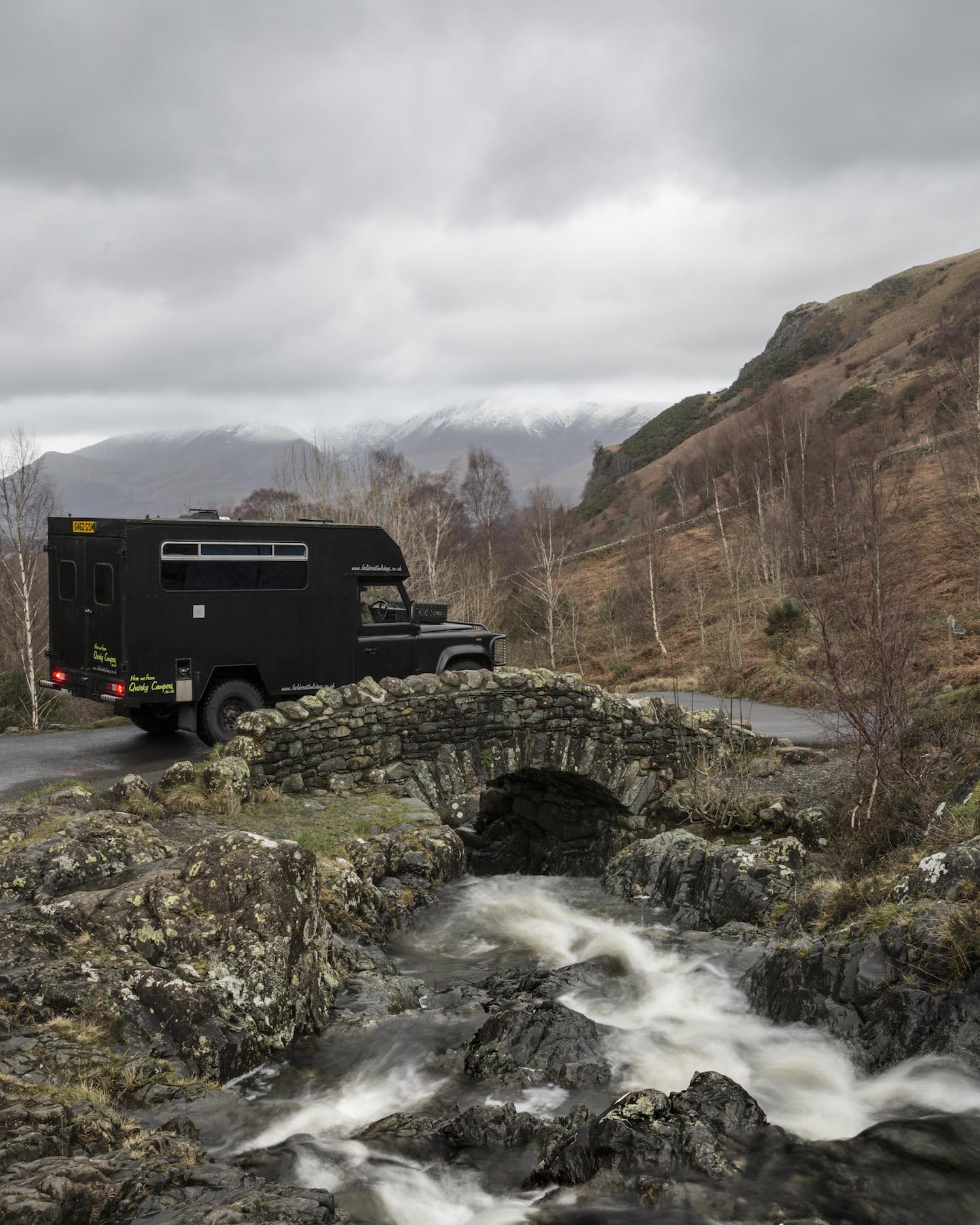A campervan crossing a tiny stream bridge on an adventure holiday in UK