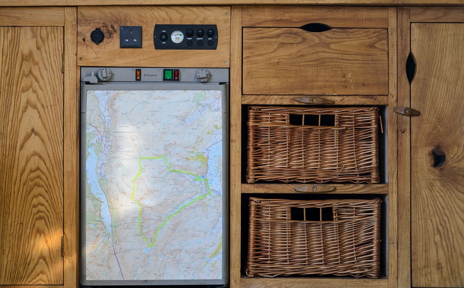 beautiful wooden campervan kitchen with fridge covered in a map