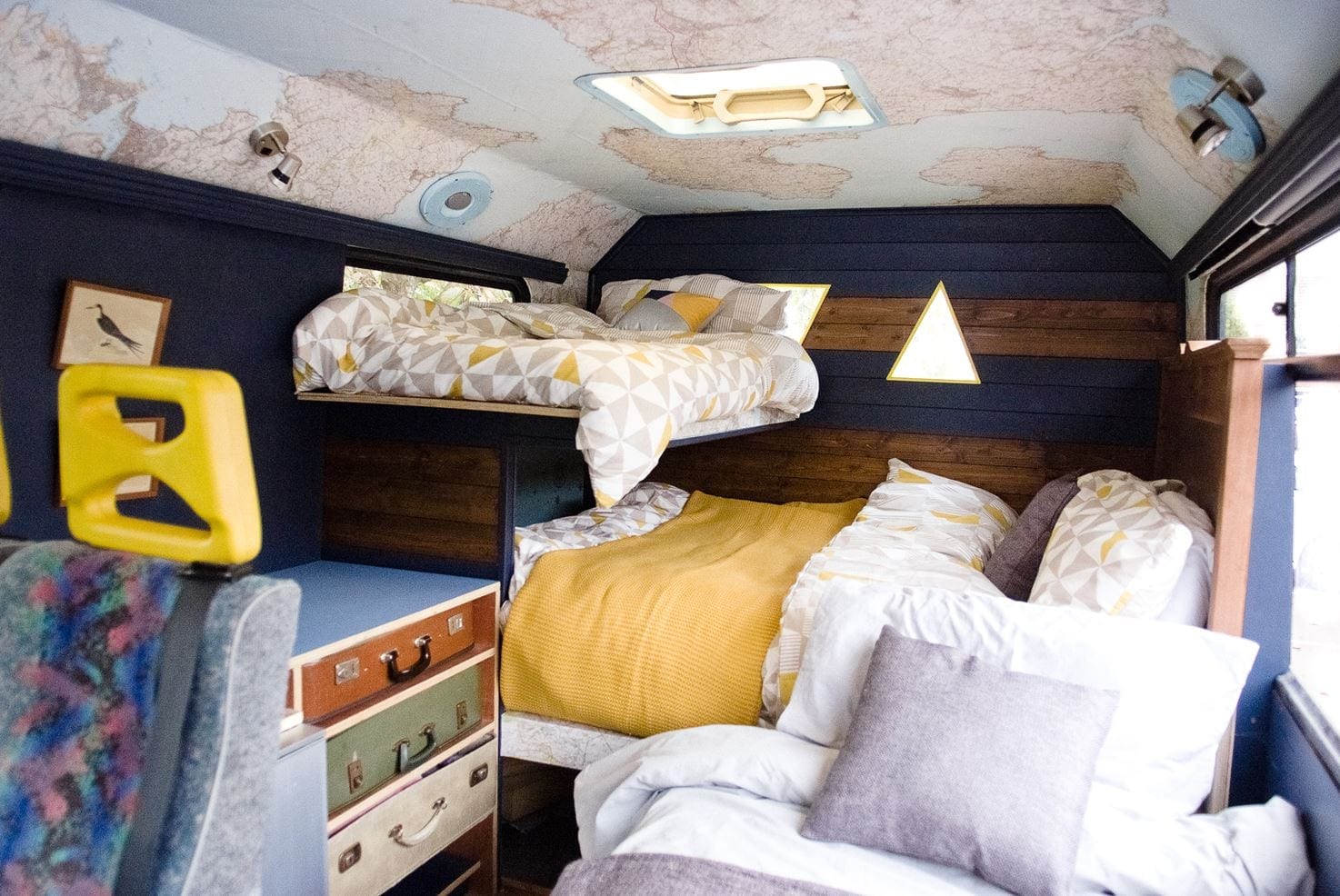 a converted selfbuilt campervan with a duble bed, single bed and maps on the ceiling