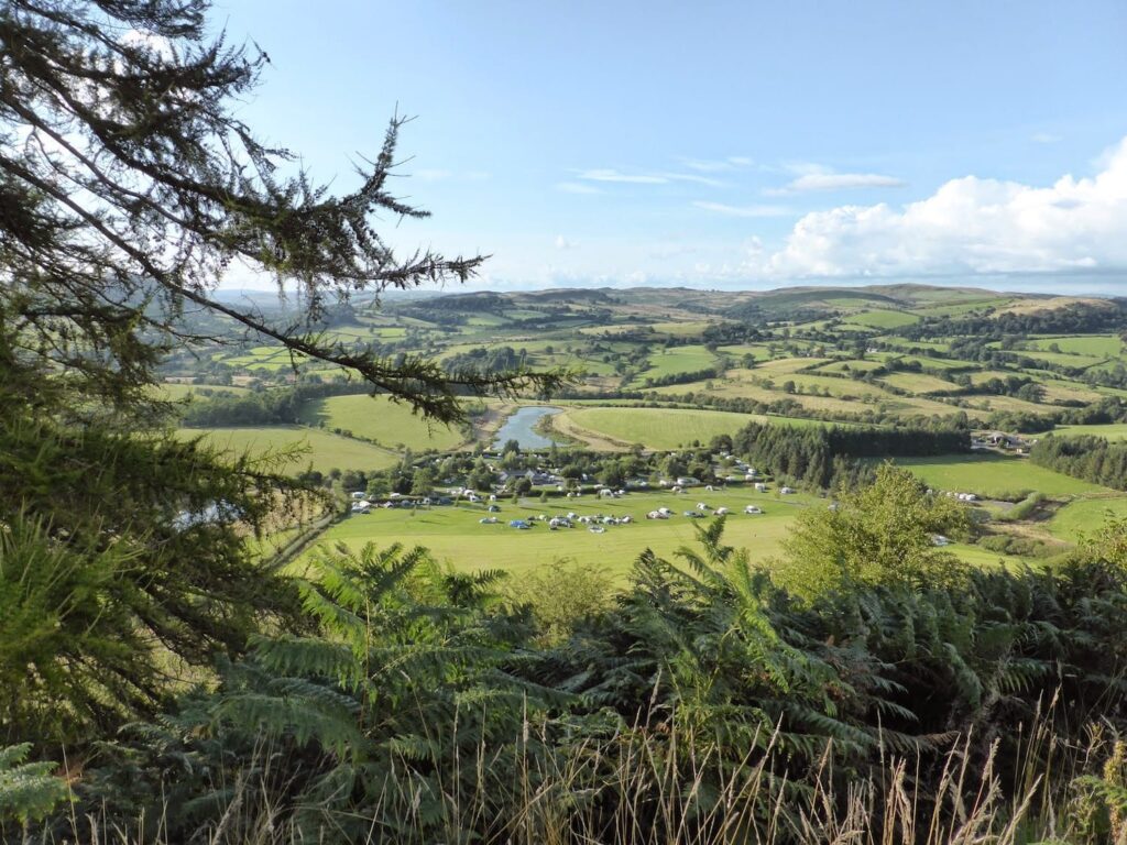A view of fields and trees and a lake in mid wales