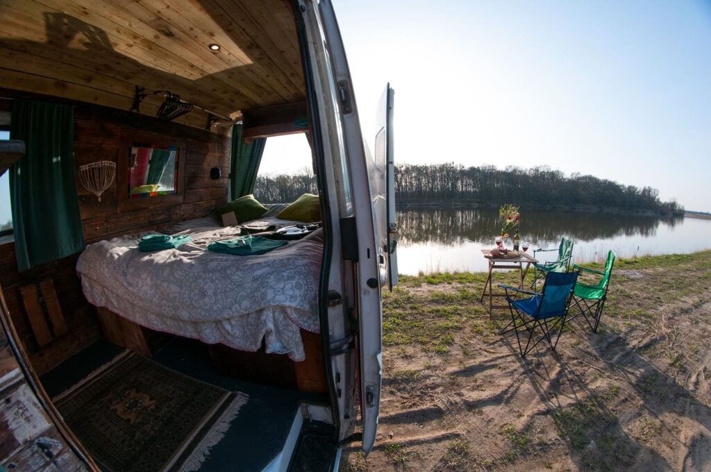 the bed and inside of a campervan looking out onto a lake