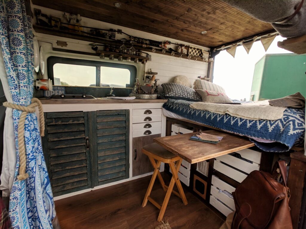 The inside of a handmade campervan including bed, dining and kitchen area