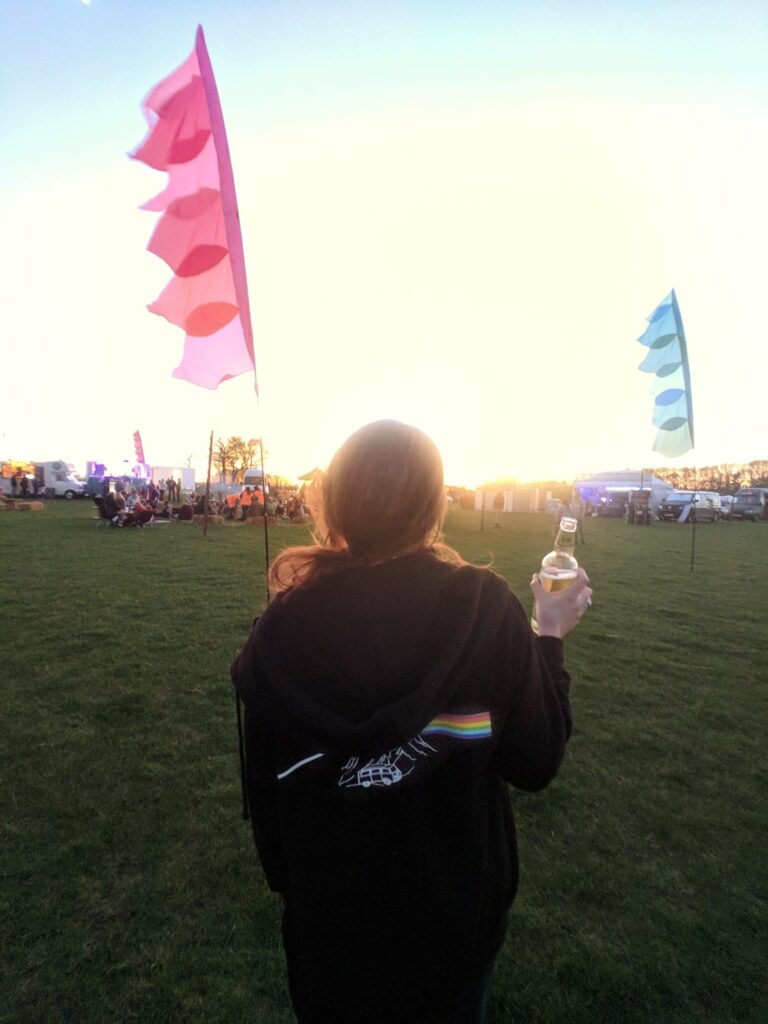 A woman walking in a festival field with festival flags in the background
