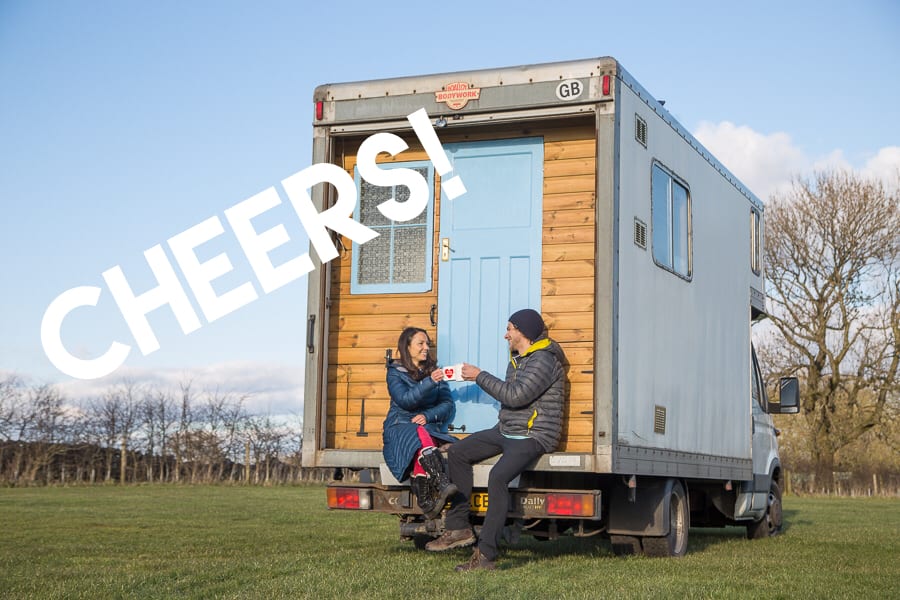 2 americans traveling the UK in a campervan making 'cheers' with coffee cups