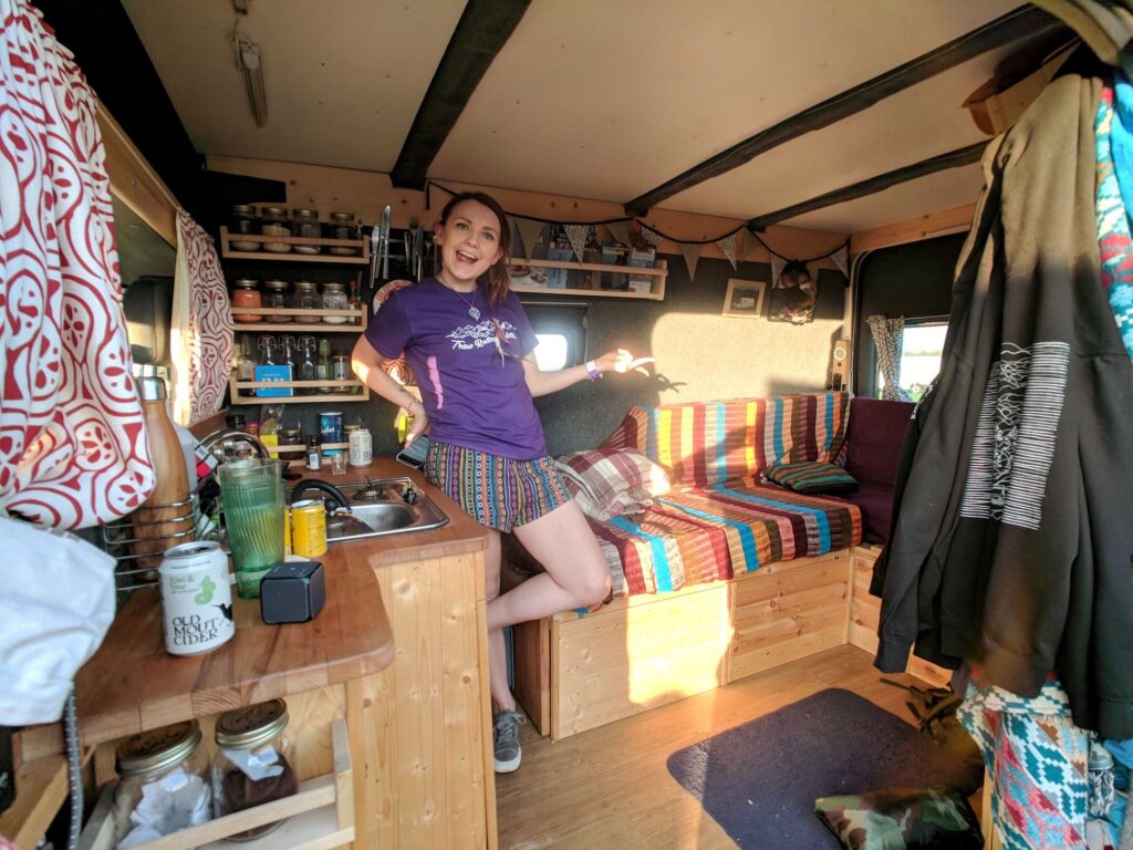 A woman showing off the inside of her selfbuilt campervan living area