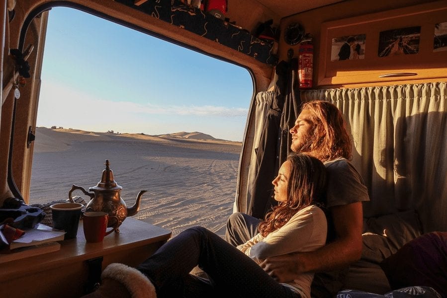Couple cuddling looking into the Moroccan sand dunes with a Moroccan tea pot on the table