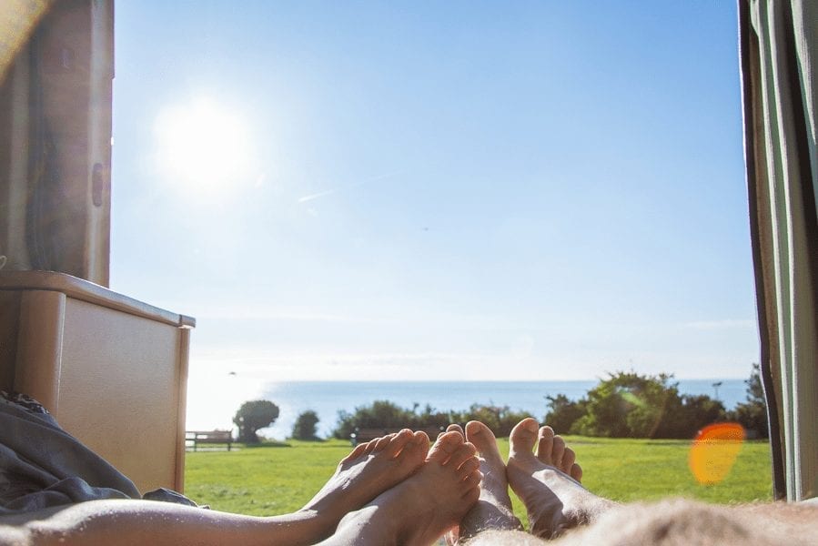 2 people lying in a campervan overlooking the sea