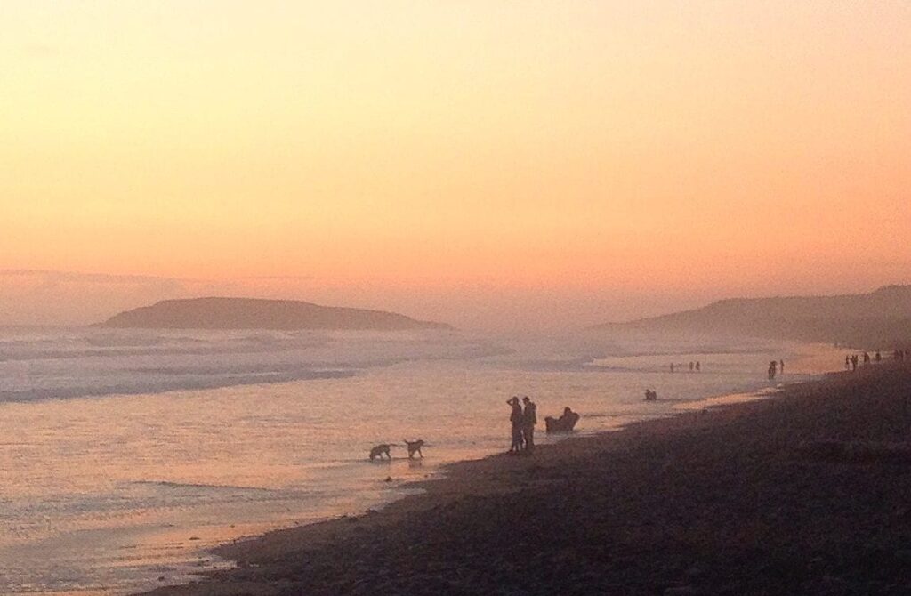 Sunset on a Welsh beach with a few people and some dogs