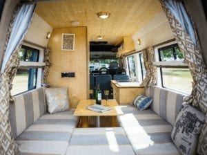 The inside of a selfbuilt campervan including sofas, table and soft furnishings